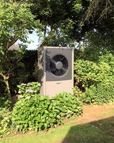 Warmtepomp-buitendeel in een groene tuin, geplaatst door Gasservice Venlo